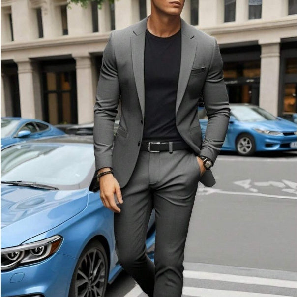Man in a gray suit standing next to a blue car on a city street.