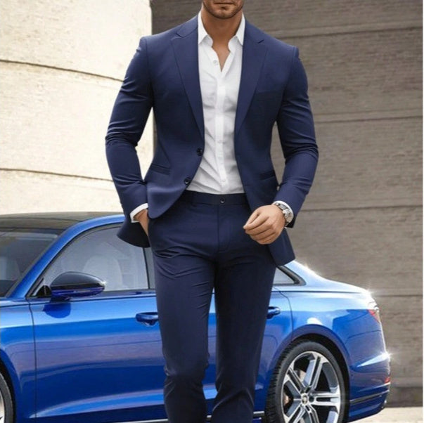 Man in a navy suit standing next to a blue car with a neutral background